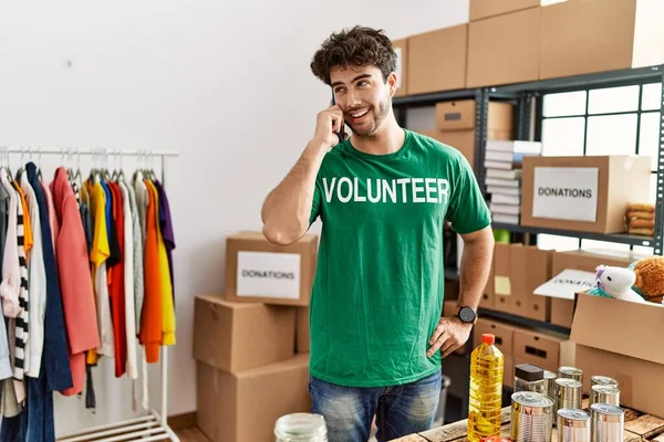 Jonge Spaanse Man Vrijwilligersuniform Gesprek Smartphone Het Liefdadigheidscentrum — Stockfoto