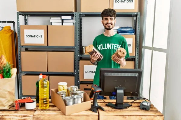 Jonge Spaanse Man Draagt Vrijwilligersuniform Houdt Voedsel Vast Een Liefdadigheidscentrum — Stockfoto