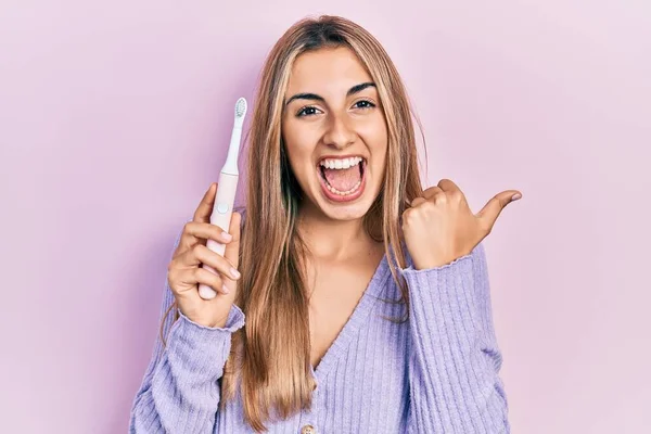 Mulher Hispânica Bonita Segurando Escova Dentes Elétrica Apontando Polegar Até — Fotografia de Stock