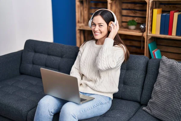 Evdeki Kanepede Oturan Dizüstü Bilgisayar Kulaklık Kullanan Genç Bir Kadın — Stok fotoğraf