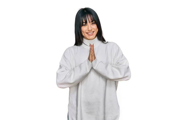 若いですブルネット女性とともに手で祈るカジュアルなタートルネックセーターを身に着けているバングとともに許し笑顔自信を求めて — ストック写真