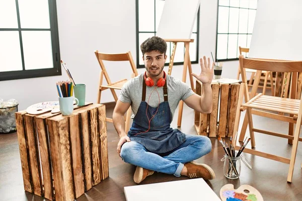 Ung Latinamerikansk Man Sitter Konststudio Visar Och Pekar Upp Med — Stockfoto