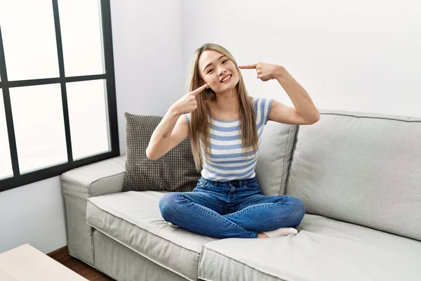 Asiática Joven Sentada Sofá Casa Sonriendo Alegre Mostrando Señalando Con —  Fotos de Stock