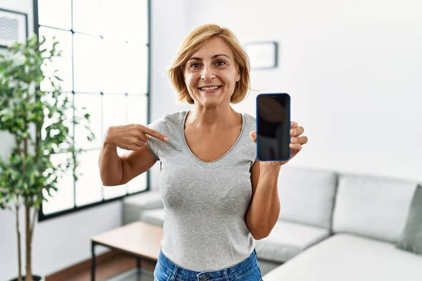 Mulher Loira Meia Idade Trabalhando Segurando Smartphone Mostrando Tela Apontando — Fotografia de Stock