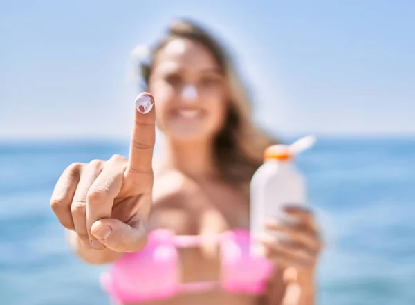 若いですブロンド女の子身に着けていますビキニショー指とともに日焼け止めローションでザビーチ — ストック写真