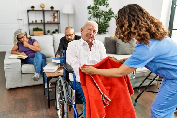 老人ホームで車椅子に座って引退した男性をサポートする中年の医師の女性 — ストック写真