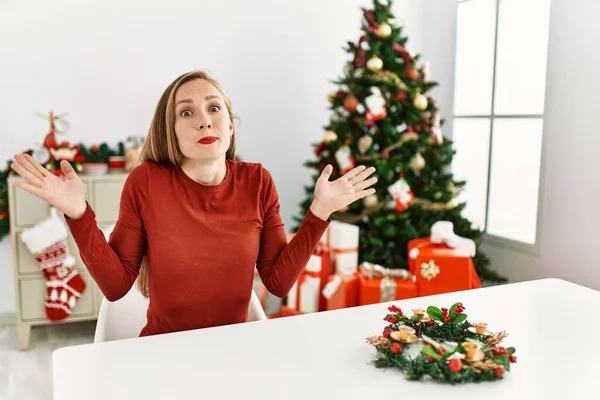 Kavkazská Mladá Blondýnka Sedící Stole Vánočního Stromku Bezradný Zmatený Výraz — Stock fotografie