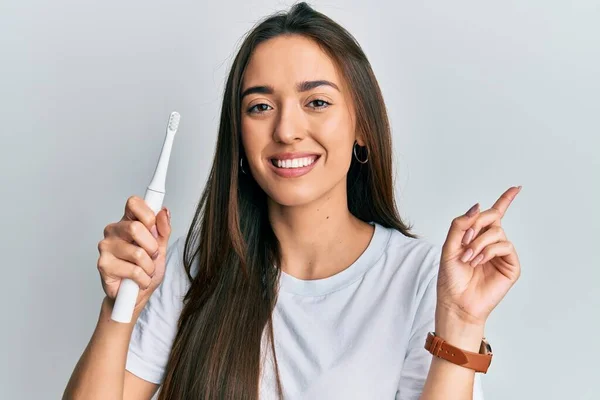 Joven Chica Hispana Sosteniendo Cepillo Dientes Eléctrico Sonriendo Feliz Señalando —  Fotos de Stock