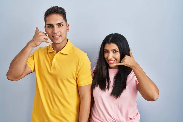 Young Couple Standing Isolated Background Smiling Doing Phone Gesture Hand — Stock Photo, Image