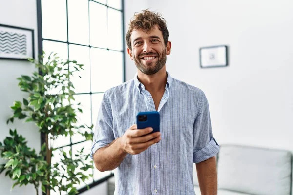 Evde Akıllı Telefon Kullanan Yakışıklı Bir Genç Olumlu Mutlu Görünüyor — Stok fotoğraf