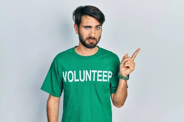 Jovem Hispânico Vestindo Camiseta Voluntária Apontando Com Dedo Mão Para — Fotografia de Stock