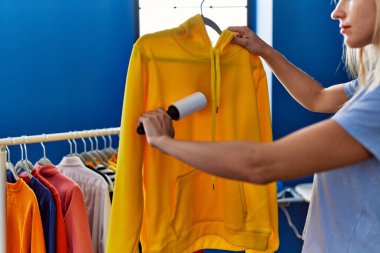 Çamaşır odasında saç fırçasıyla giysileri temizleyen genç sarışın kadın.