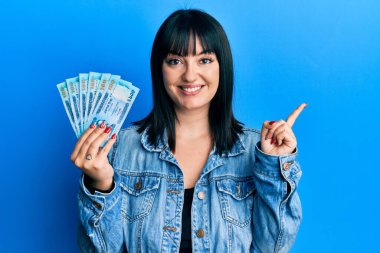 Bangladeş 'i tutan genç İspanyol kadın, gülümseyen banknotlar, mutlu bir şekilde el ve parmak kenarı gösteriyor. 