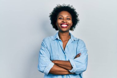 Sıradan kıyafetler giyen, kollarını kavuşturup kameraya gülümseyen genç Afrikalı Amerikalı kadın. pozitif kişi. 