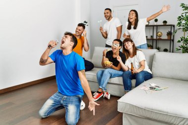 Bir grup genç arkadaş evde mikrofon kullanarak şarkı söylüyor..