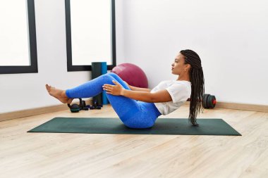 Genç Afrikalı Amerikalı kadın spor merkezinde karın kaslarını çalıştırıyor.