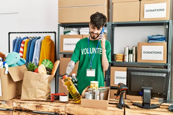 Gönüllü üniformalı genç İspanyol bir adam yardım merkezindeki akıllı telefondan konuşuyor..