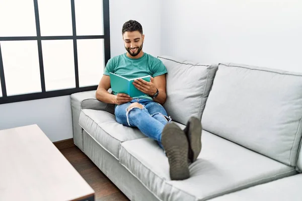 Jeune Homme Arabe Lecture Livre Couché Sur Canapé Maison — Photo