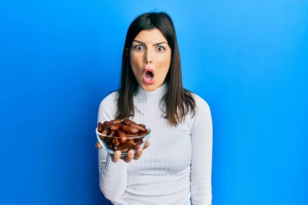 Young Hispanic Woman Holding Dates Bowl Scared Amazed Open Mouth — Stock Photo, Image