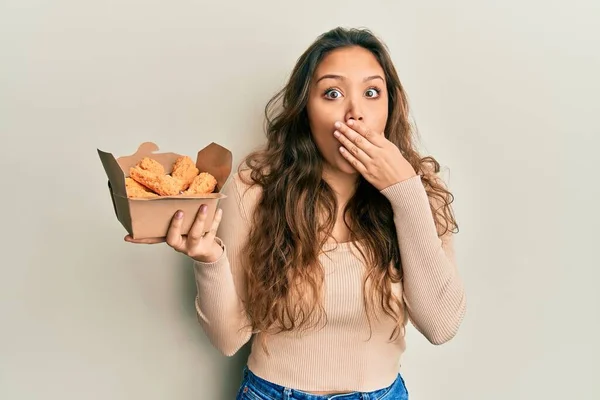 Jovem Hispânica Comendo Asas Frango Cobrindo Boca Com Mão Chocada — Fotografia de Stock