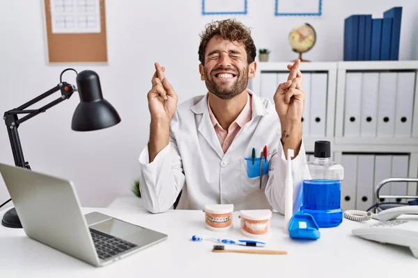 Jovem Dentista Hispânico Trabalhando Clínica Médica Gesto Dedo Cruzado Sorrindo — Fotografia de Stock
