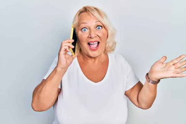 Mulher Loira Meia Idade Conversando Smartphone Celebrando Realização Com Sorriso — Fotografia de Stock