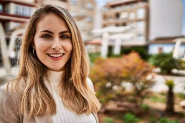 Sokakta kendinden emin gülümseyen genç sarışın kadın