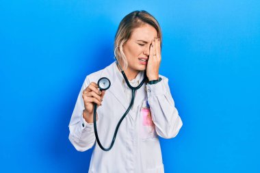 Güzel sarışın doktor kadın steteskop tutuyor. Yüzünün yarısını, gözünü ve ağzını eliyle kapatmaktan yorulmuş. Yüzüm acıyor.. 