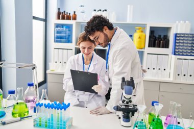 Erkek ve kadın bilim adamları laboratuarda çalışıyor.