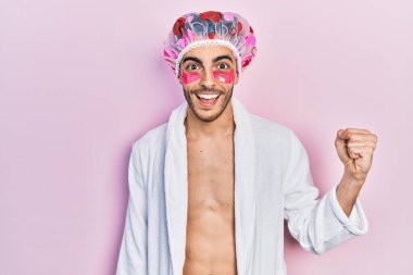 Bornoz ve duş başlığı takan genç İspanyol adam. Göz torbaları kullanıyor. Gururla bağırıyor, zaferi kutluyor ve başarıyı kollarını kaldırarak kutluyor. 