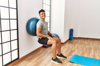 Genç İspanyol gülen adam spor merkezinde formda top kullanarak kendine güvenen bir antrenman yapıyor.