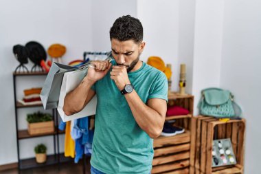 Satış mağazasında sakallı yakışıklı bir adam kendini iyi hissetmiyor ve soğuk algınlığı veya bronşitin belirtisi olarak öksürüyor. sağlık hizmeti kavramı. 