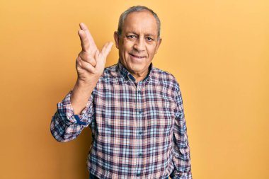 Yakışıklı, gri saçlı, sıradan tişörtlü üç numaralı parmaklarıyla gösteriş yapan kendinden emin ve mutlu bir şekilde gülümseyen son sınıf öğrencisi.. 