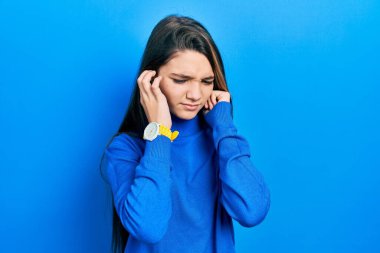 Balıkçı yaka kazak giyen genç esmer kız yüksek sesli müzik sesi için kulaklarını parmaklarıyla kapatıyor. sağır kavramı. 