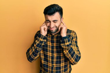 Gürültülü müzik sesi için günlük kıyafetler giyen genç İspanyol adam kulaklarını parmaklarıyla kapatıyor. sağır kavramı. 