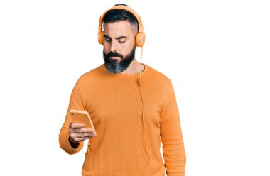 Sakallı, akıllı telefon kullanan, kulaklık takan, aklı başında, aklı başında, kendine güvenen İspanyol bir adam. 