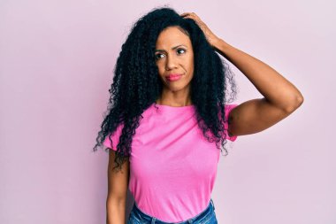 Orta yaşlı Afro-Amerikan kadın günlük giysiler giyiyor. Kafasını karıştırıyor ve soru soruyor. Şüpheyle kararsız, kafa kafaya düşünerek. Düşünceli kavram. 