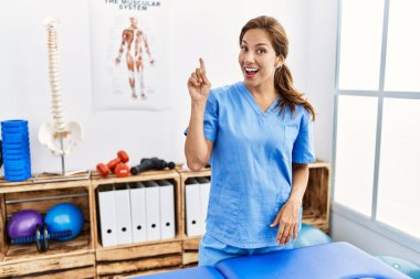 Orta yaşlı İspanyol fizyoterapist kadın ağrı kesici kliniğinde çalışıyor başarılı bir fikirle işaret ediyor. Heyecanlı ve mutlu. Bir numara.. 