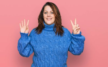 Genç ve cüsseli kadın günlük kıyafetler giyer ve yedinci parmaklarını göstererek gülümseyerek mutlu ve kendinden emin görünürler.. 