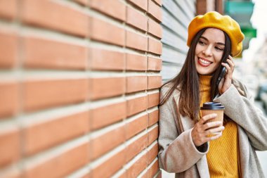 Genç İspanyol kız akıllı telefonda konuşuyor. Şehirde kahve içiyor..