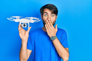 Genç İspanyol asıllı bir adam drone 'u elinde tutarak ağzını eliyle kapatıyor, şok geçiriyor ve hata yapmaktan korkuyor. şaşırmış ifade 