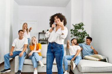 Bir grup genç arkadaş evde mikrofon kullanarak şarkı söylüyor..