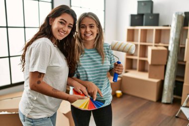 Genç çift yeni evinde boya rengi silindiri seçiyor..