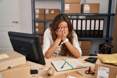 Küçük işletme şirketinde çalışan genç İspanyol bir kadın. Ağlarken yüzünü ellerle kapatan üzgün bir ifadeyle. depresyon kavramı. 