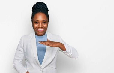 Genç Afro-Amerikalı kadın iş kıyafetleri giyiyor. Elleriyle işaret ediyor. Büyük ve büyük boy, ölçü sembolü. Kameraya bakıp gülümsüyor. ölçüm kavramı. 