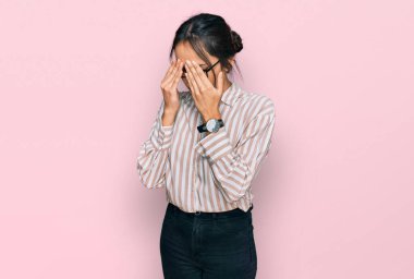 Günlük kıyafetler giyen ve gözlük takan genç İspanyol kız yorgunluk ve baş ağrısı için gözlerini ovuşturuyor, uykulu ve yorgun bir ifade takınıyor. görme sorunu 