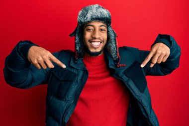 Sakallı, kışlık şapkalı ve paltolu, kendine güvenen, yüzünde gülümsemeyle gururlu ve mutlu bir şekilde kendini gösteren Afrikalı genç bir Amerikalı.. 