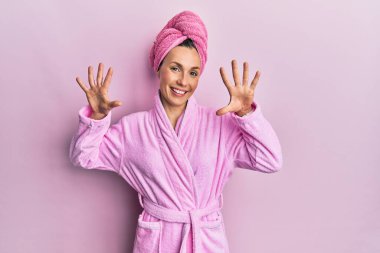 Duş başlığı ve bornoz takan genç sarışın kadın on numarayı gösterip işaret ederken kendinden emin ve mutlu bir şekilde gülümsüyor.. 