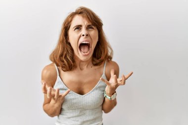 Güzel, beyaz bir kadın izole arka planda duruyor. Deli gibi bağırıyor, bağırıyor, agresif bir ifade ve kollarla bağırıyor. hüsran kavramı. 
