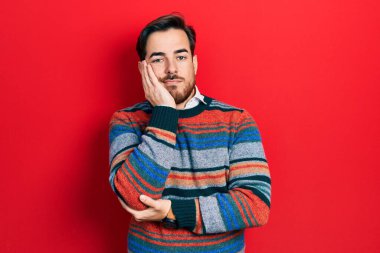 Sakallı, zarif yün kazak giyen yakışıklı beyaz adam çapraz kollu depresyondan sıkılmış ve yorgun görünüyor.. 